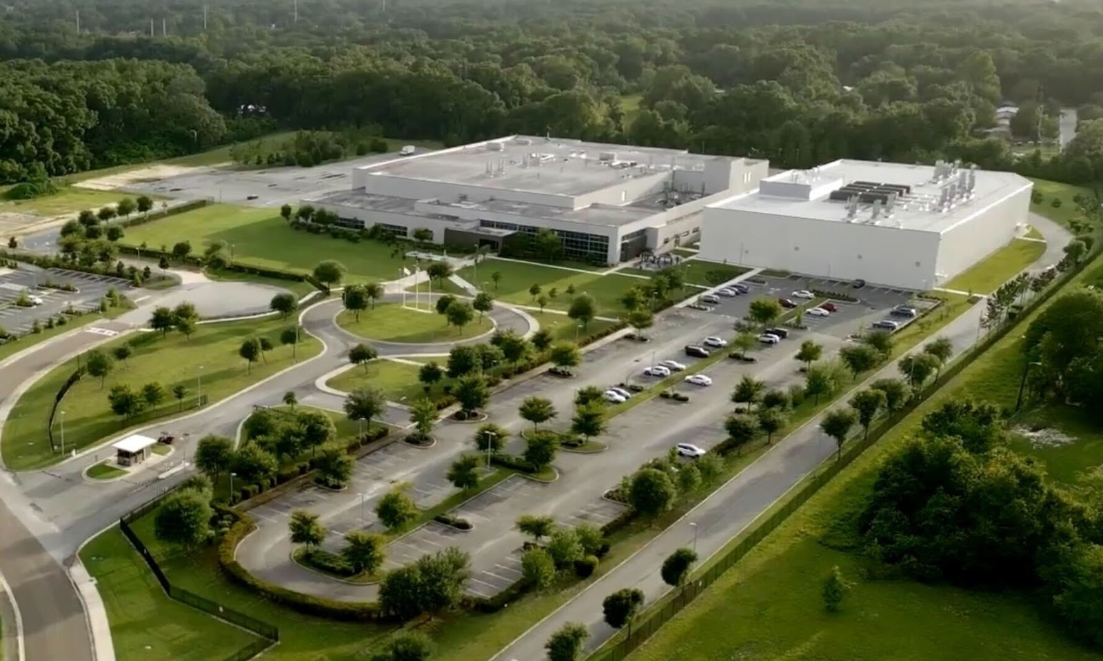 Aerial view of the Strive Pharmacy compounding facility, a large white building surrounded by manicured grounds, parking, and trees.